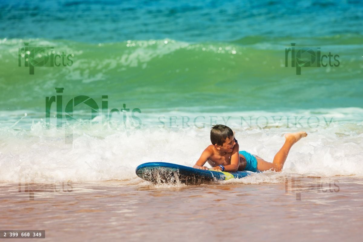 Boy lay on the beach edge practice surf movements