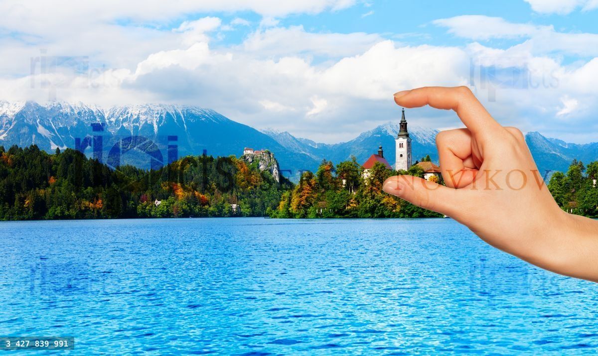 Hand holding bell tower of Bled church from afar