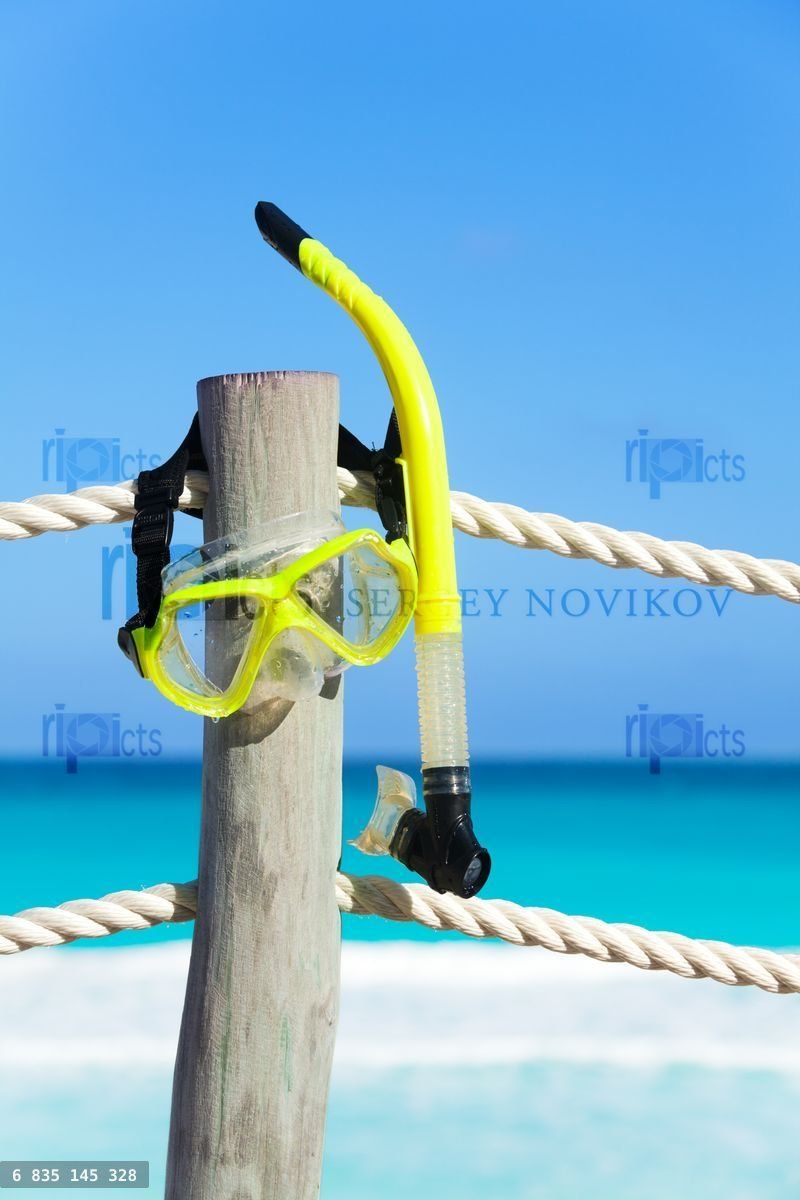 Yellow snorkeling mask hanging on the wooden stake