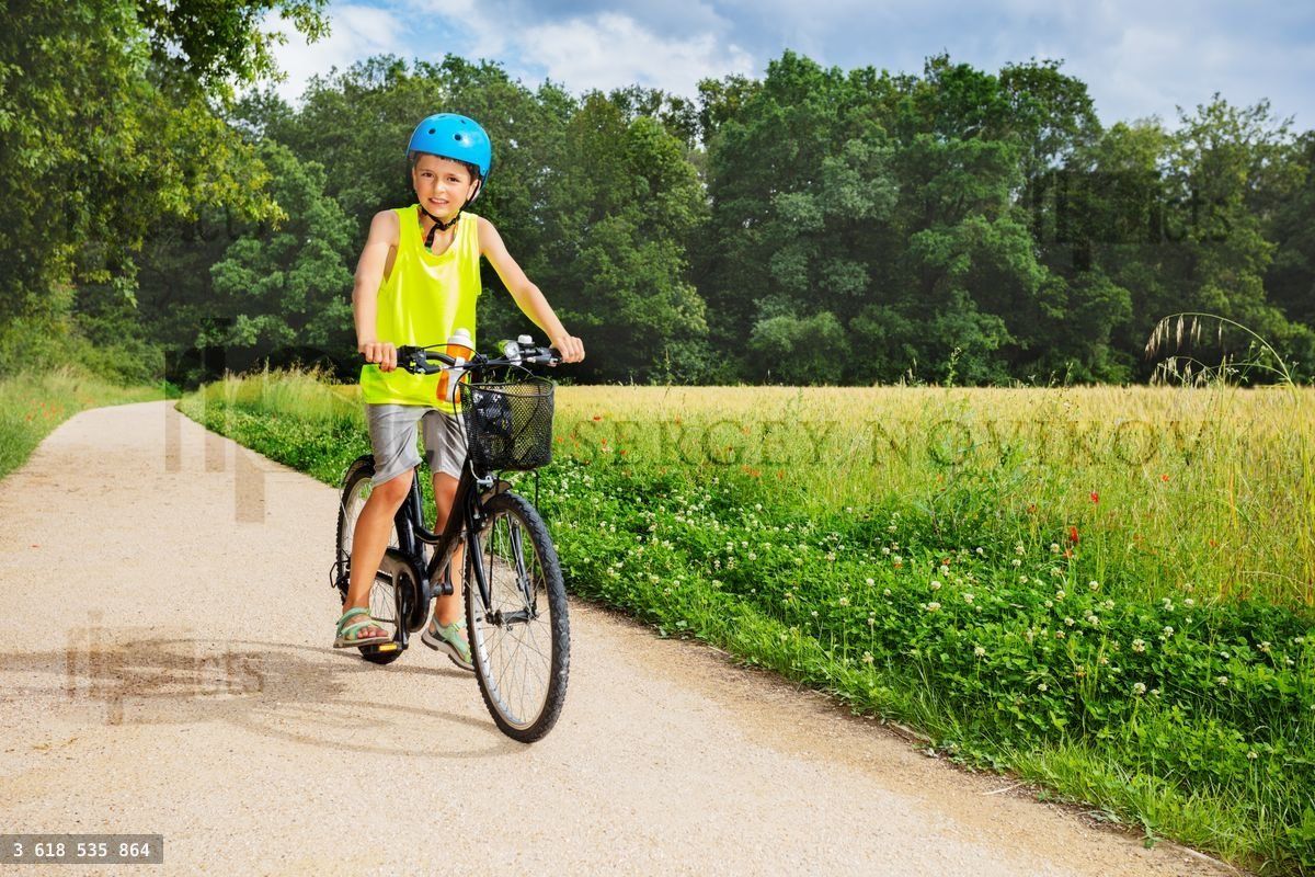 Young boy sit and ride bicycle in the park near field