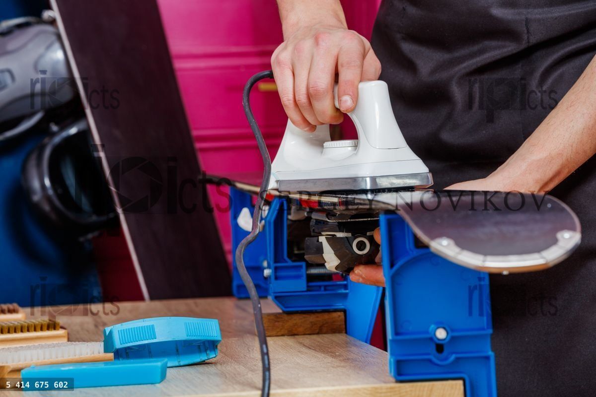 Closeup of waxing iron spread wax on ski base