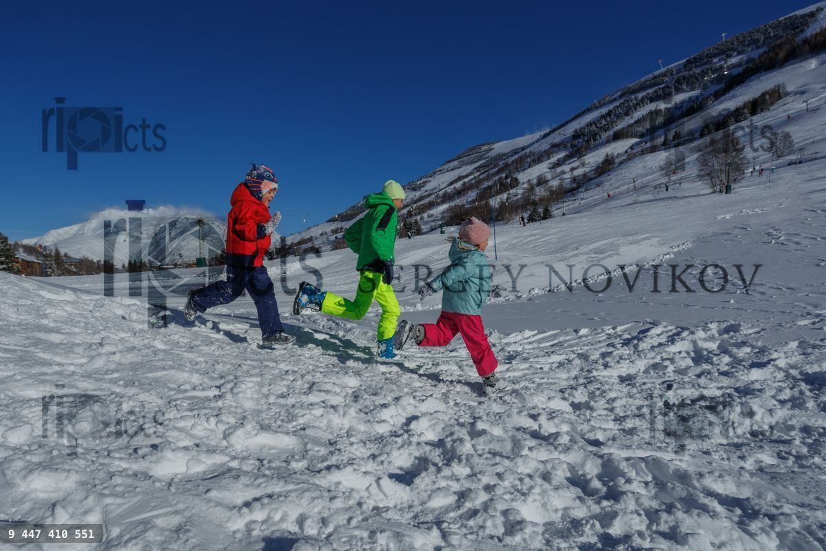 Enfants heureux, frères et sœurs courent dans une vallée de montagne enneigée, vue de profil