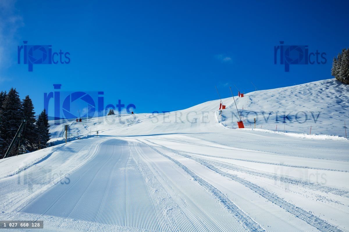 Fresh alpine ski track without people in the sunny morning