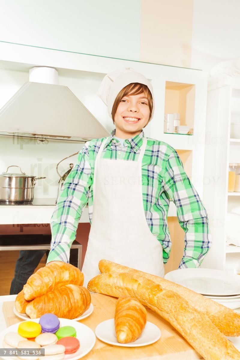 Young baker with fresh bakery food in the kitchen