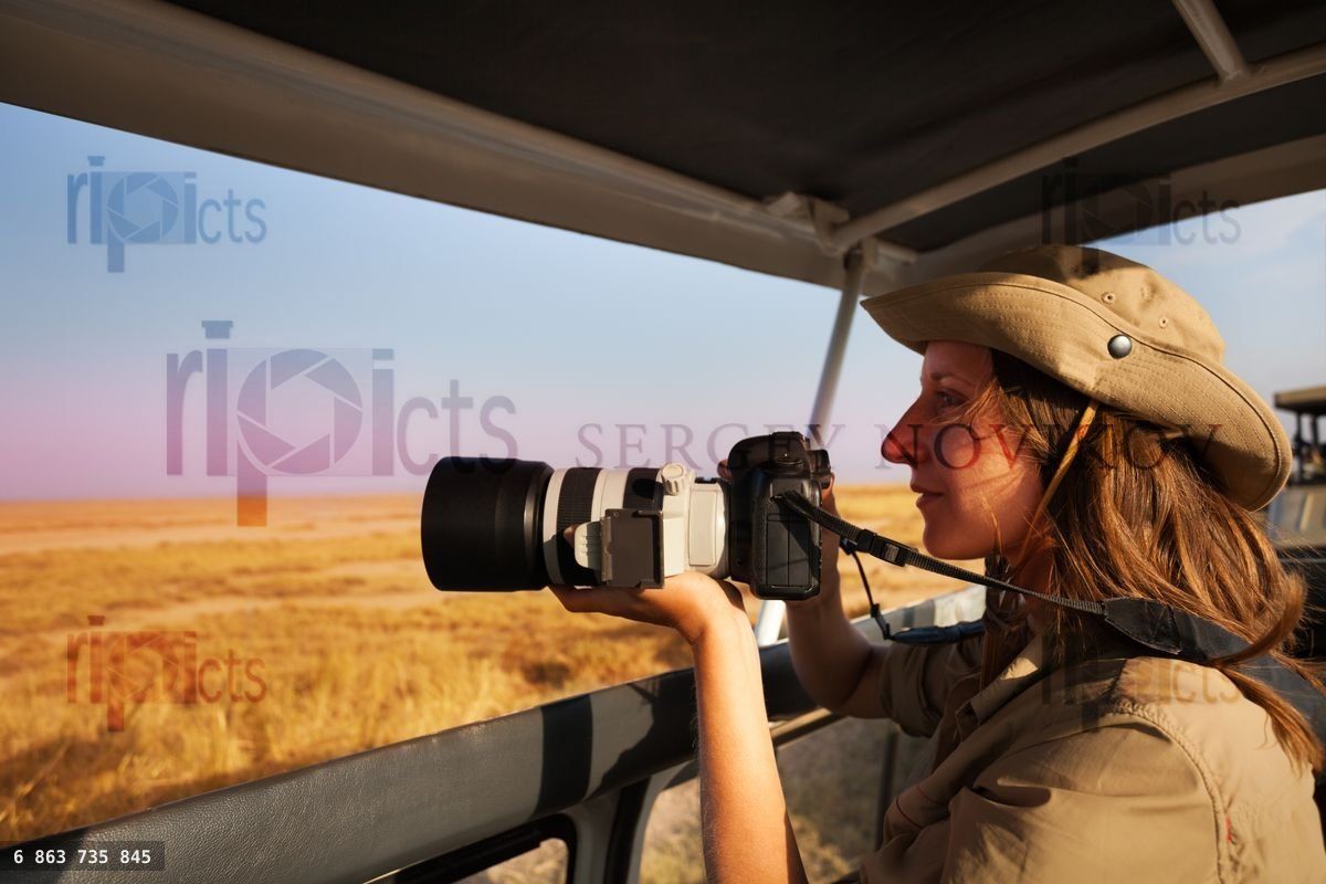 Woman taking photo aboard safari jeep at savannah
