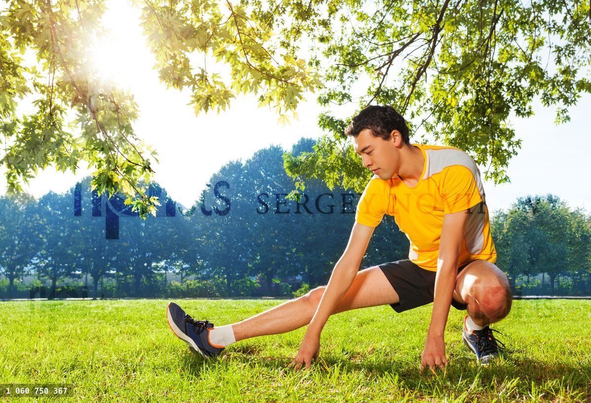 Young sportsman stretching legs before workout