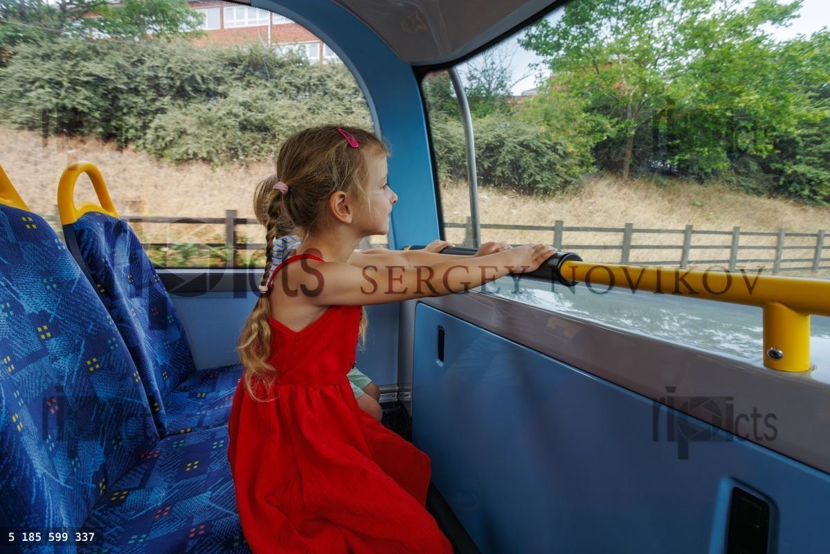 Young girl passenger enjoying bus ride while looking outside