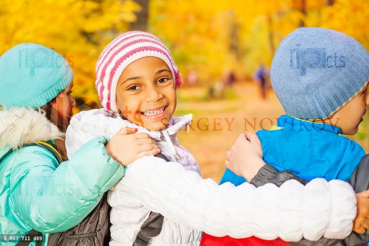 Happy children stand close with arms on shoulders
