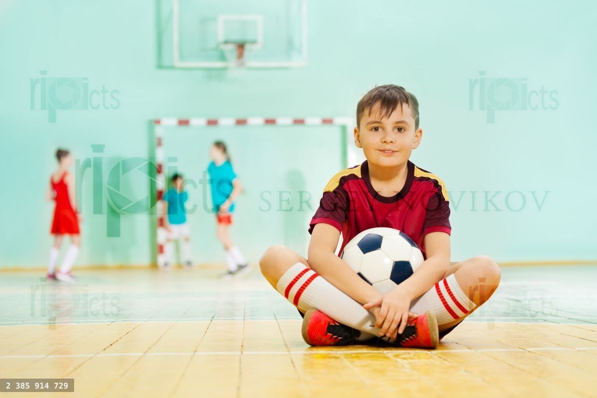 Happy boy sitting on the floor with soccer ball