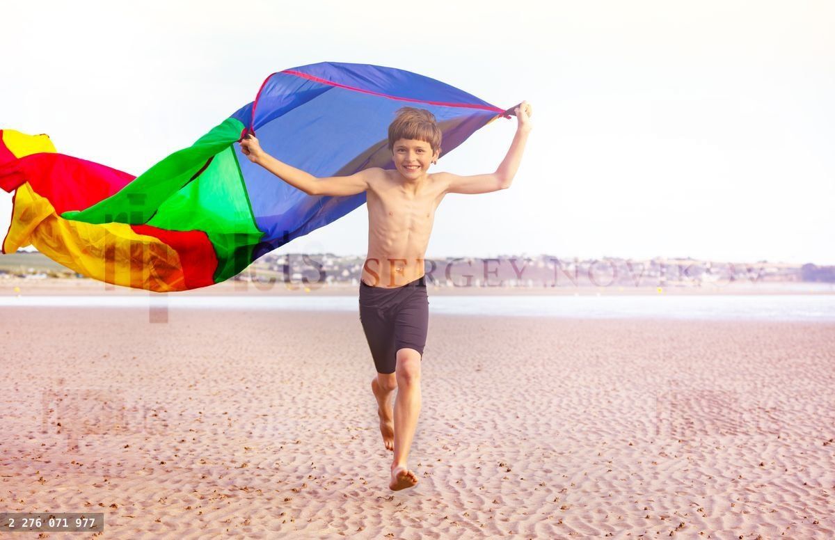 Action photo of boy run with color fabric on beach