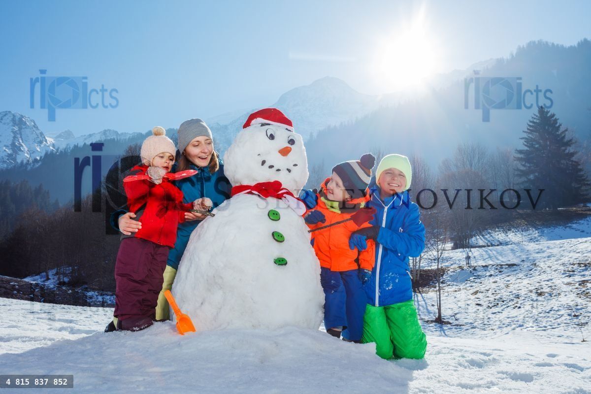 Family with mother and three children play building snowman