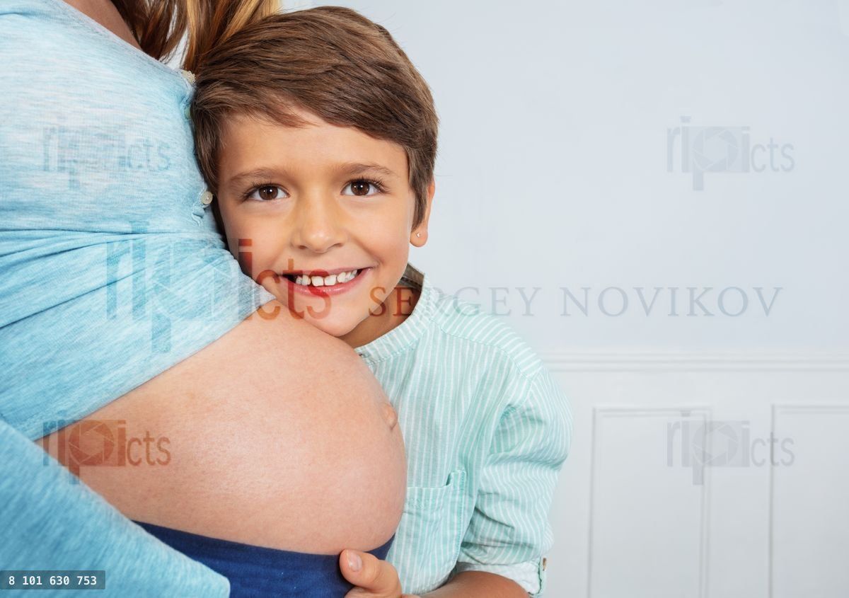 Happy son hug mom's pregnant belly close photo