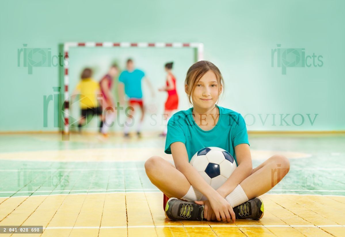 Young girl sitting on the floor with soccer ball