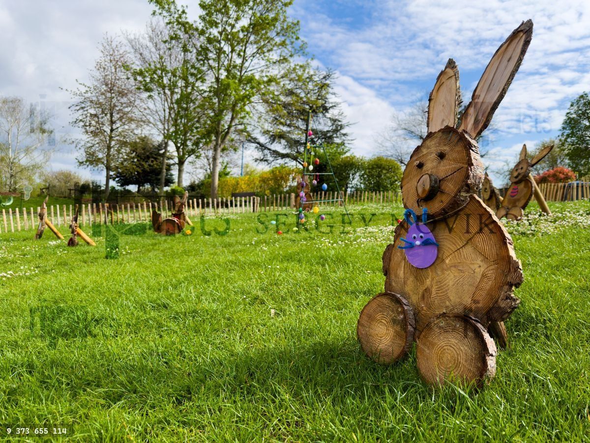 Wooden bunny sculptures in sunny meadow Easter kids decorations