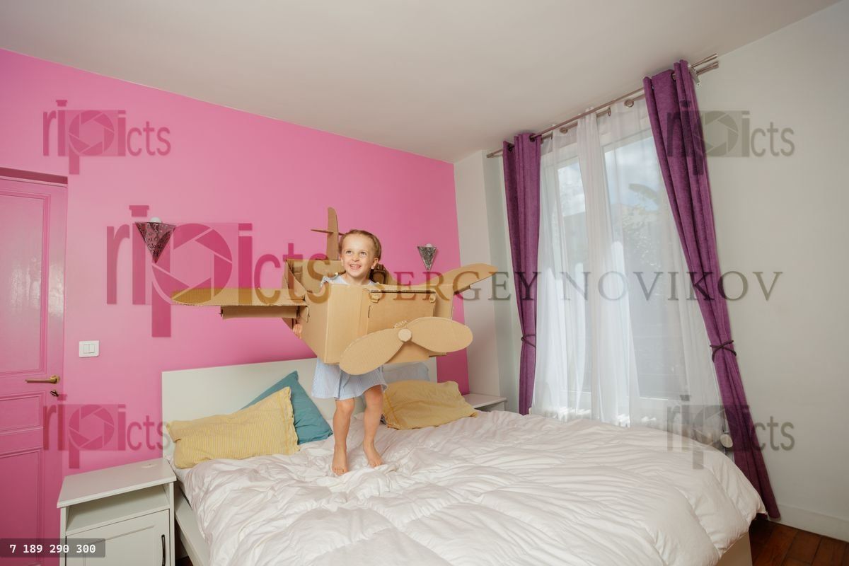 Child plays with a cardboard airplane in vibrant, cozy bedroom