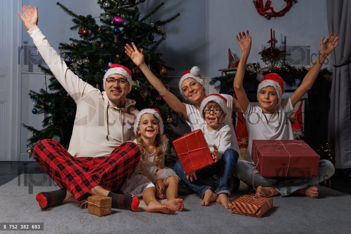 Famille souriante célèbre Noël avec des bonnets de Père Noël et des cadeaux