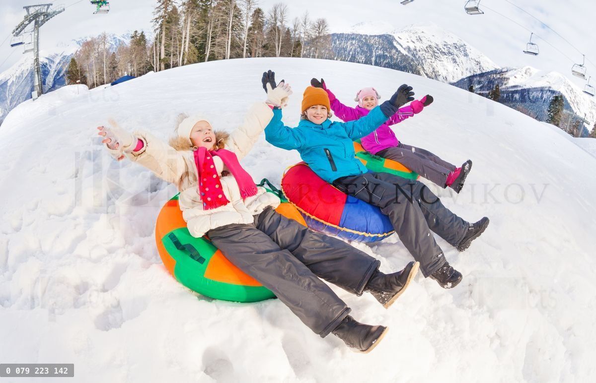 Group of children with arms up slide on tubes