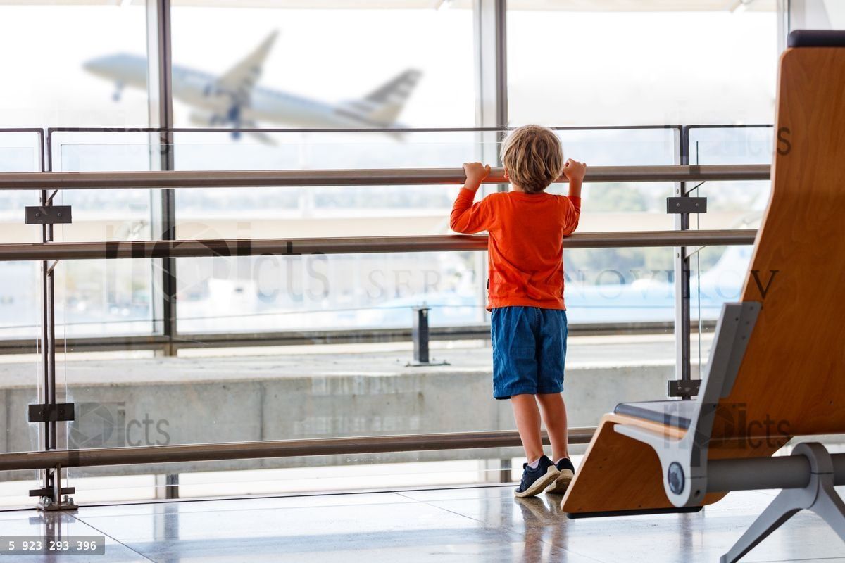 Young boy watches a plane take off from an airport window