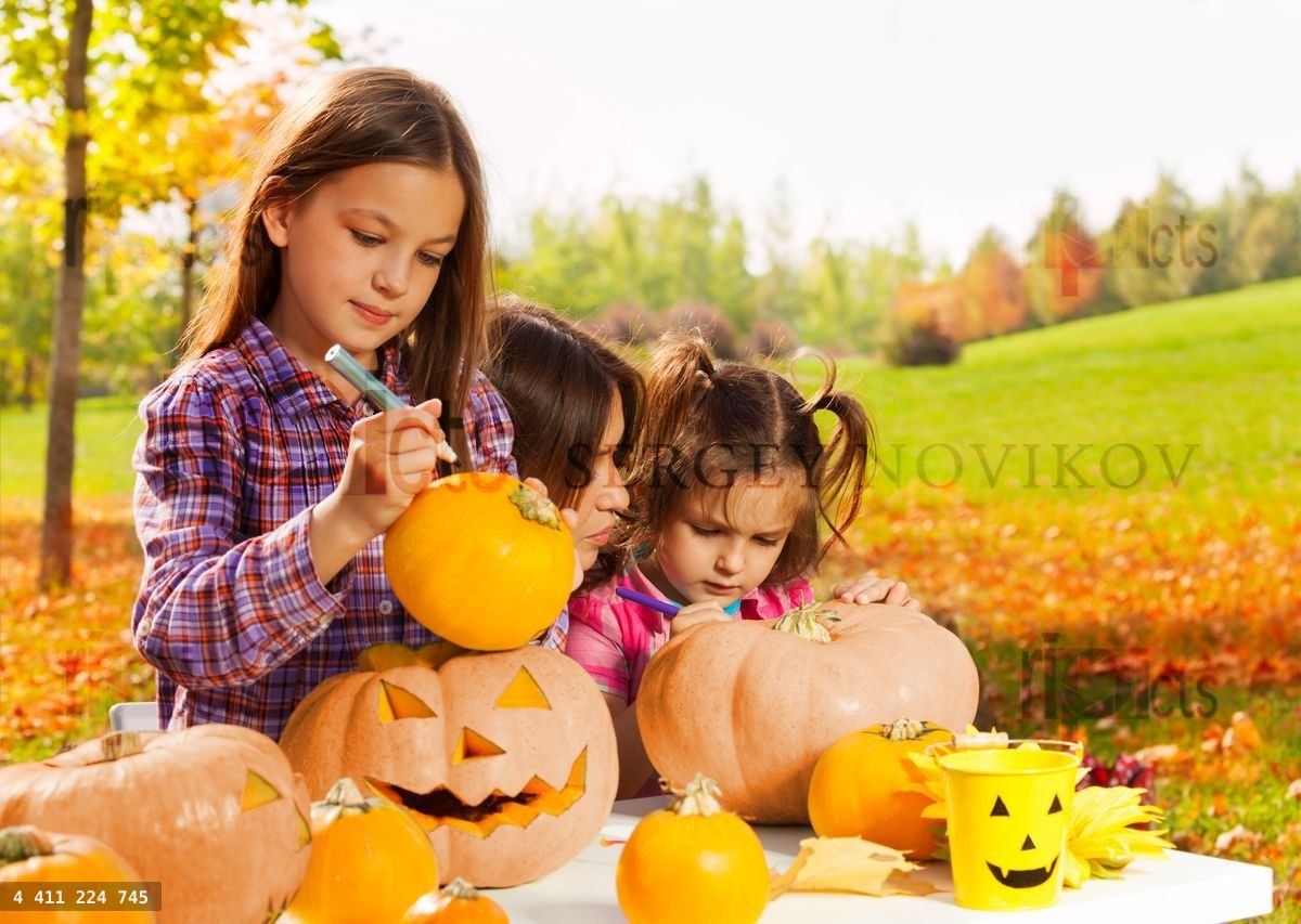 Little girl draws on Halloween pumpkin