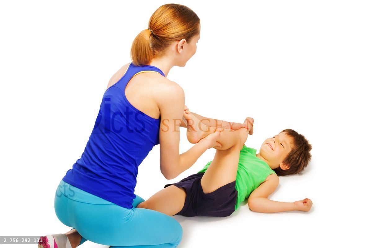 Young trainer helping boy crossing knees to elbows