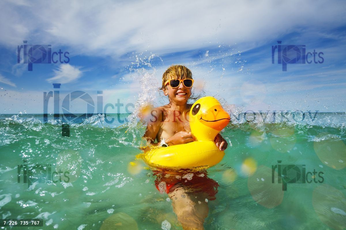 Fun in ocean boy with sunglasses and yellow inflatable duck