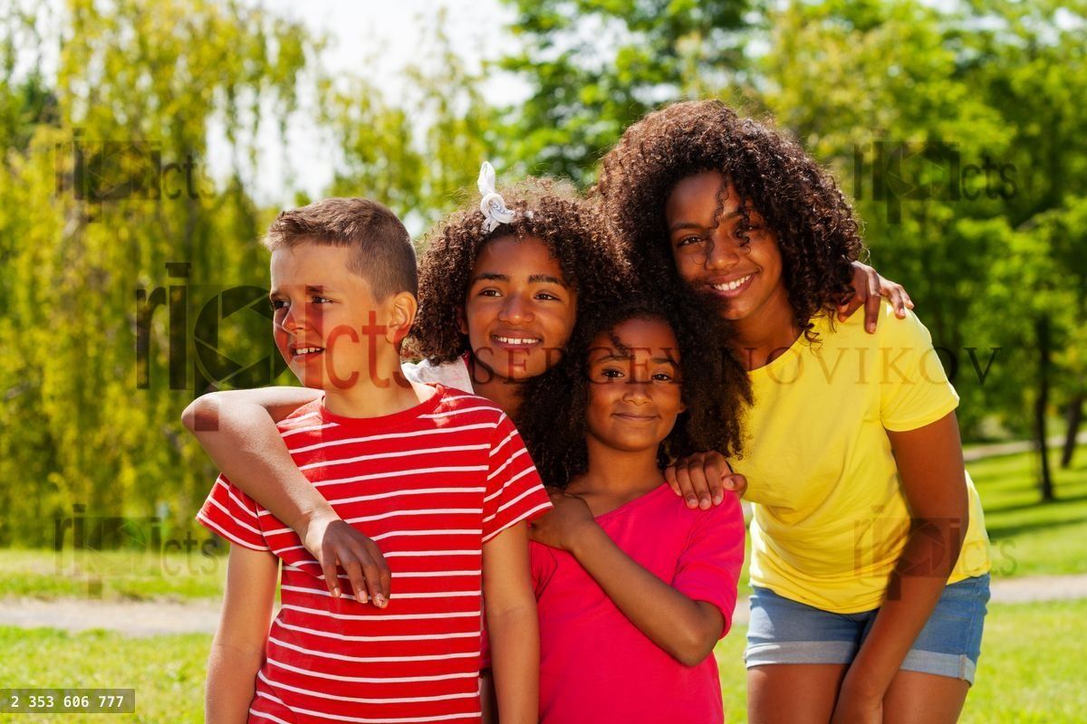 Group of cool diverse kids hug in park together