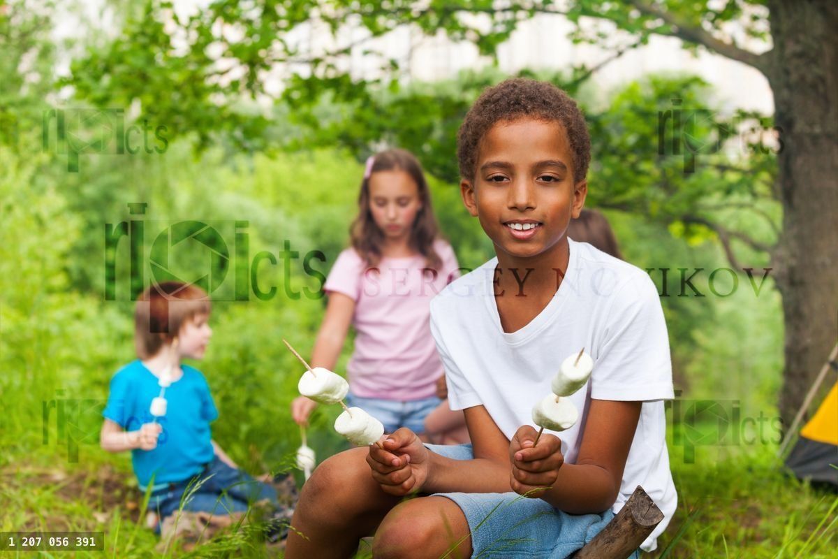 Cute African boy with marshmallows during camping