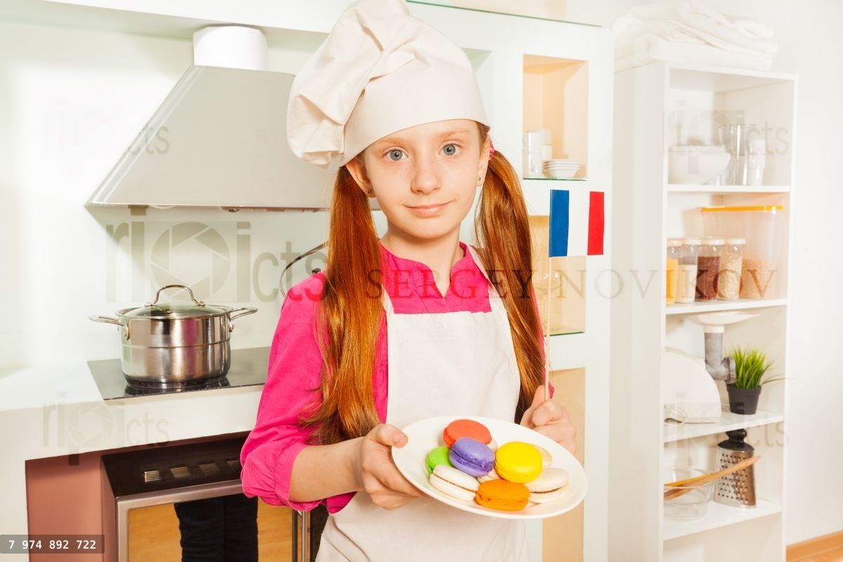 Young French baker with plate of colored macarons