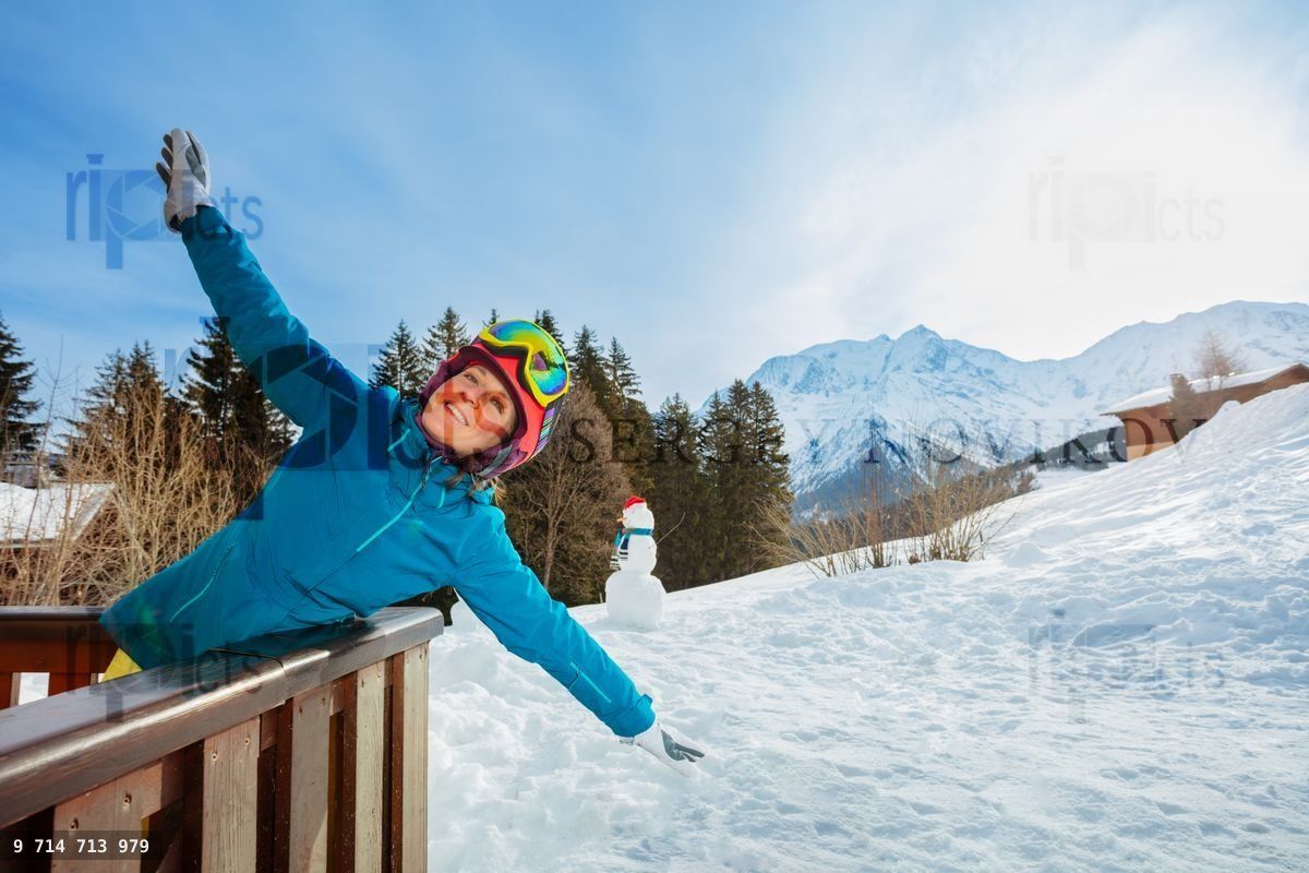 Woman stand on the balcony stretching hands wearing ski helmet
