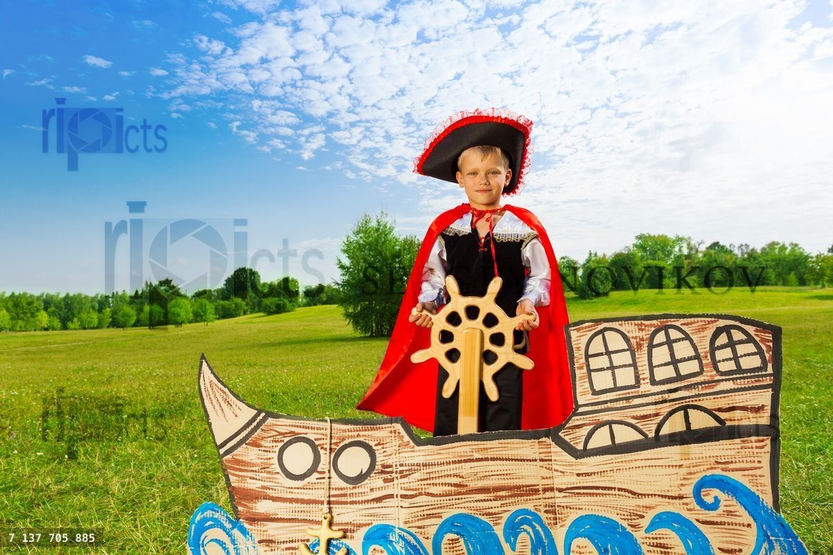 Boy as pirate stands on ship and holds the helm