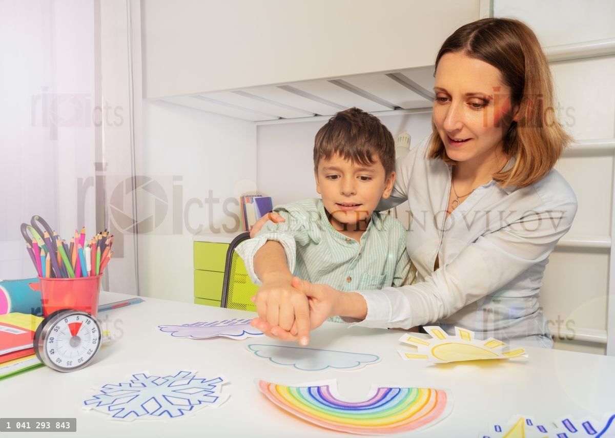 Woman during ABA therapy teach boy weather cards