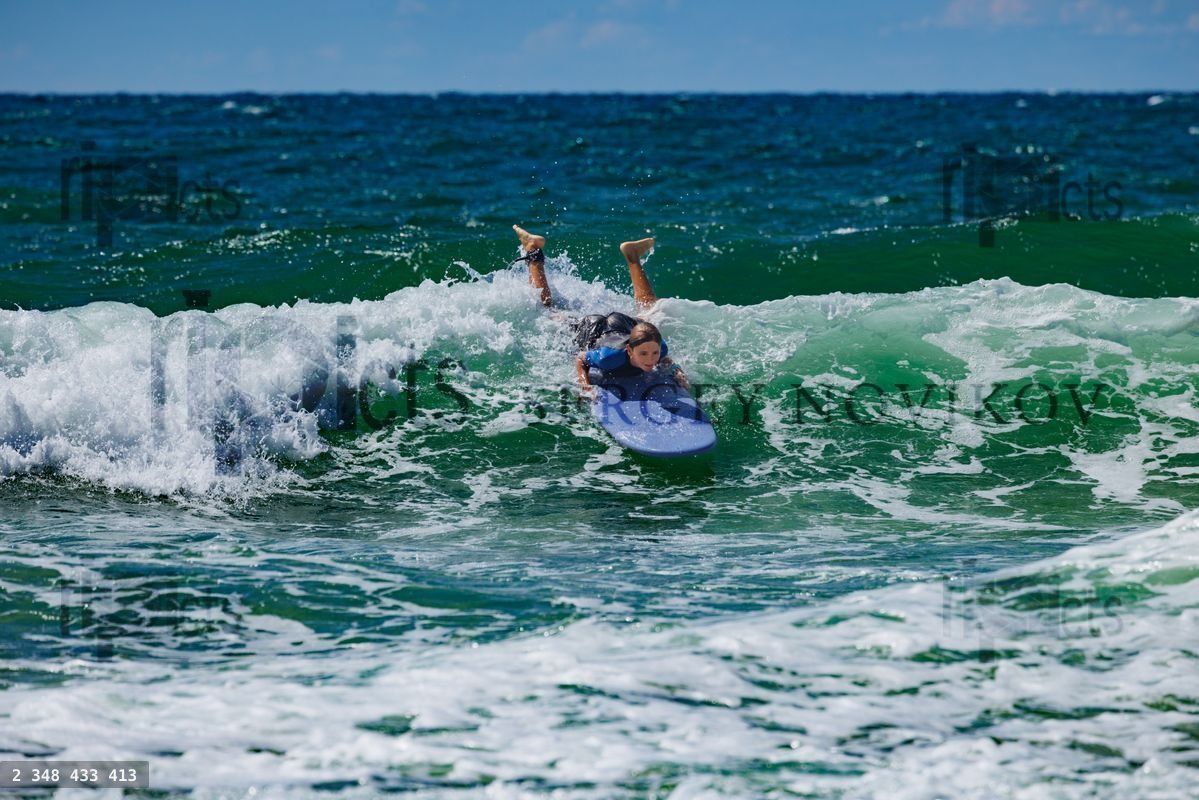 Young surfer catching a wave at the beach during surf school day