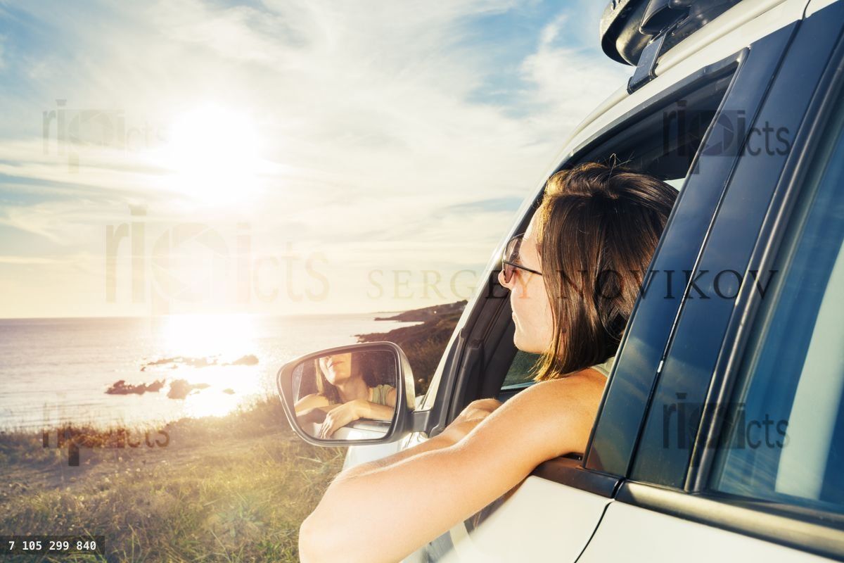 Woman on driver car window look at ocean sunset sticking out