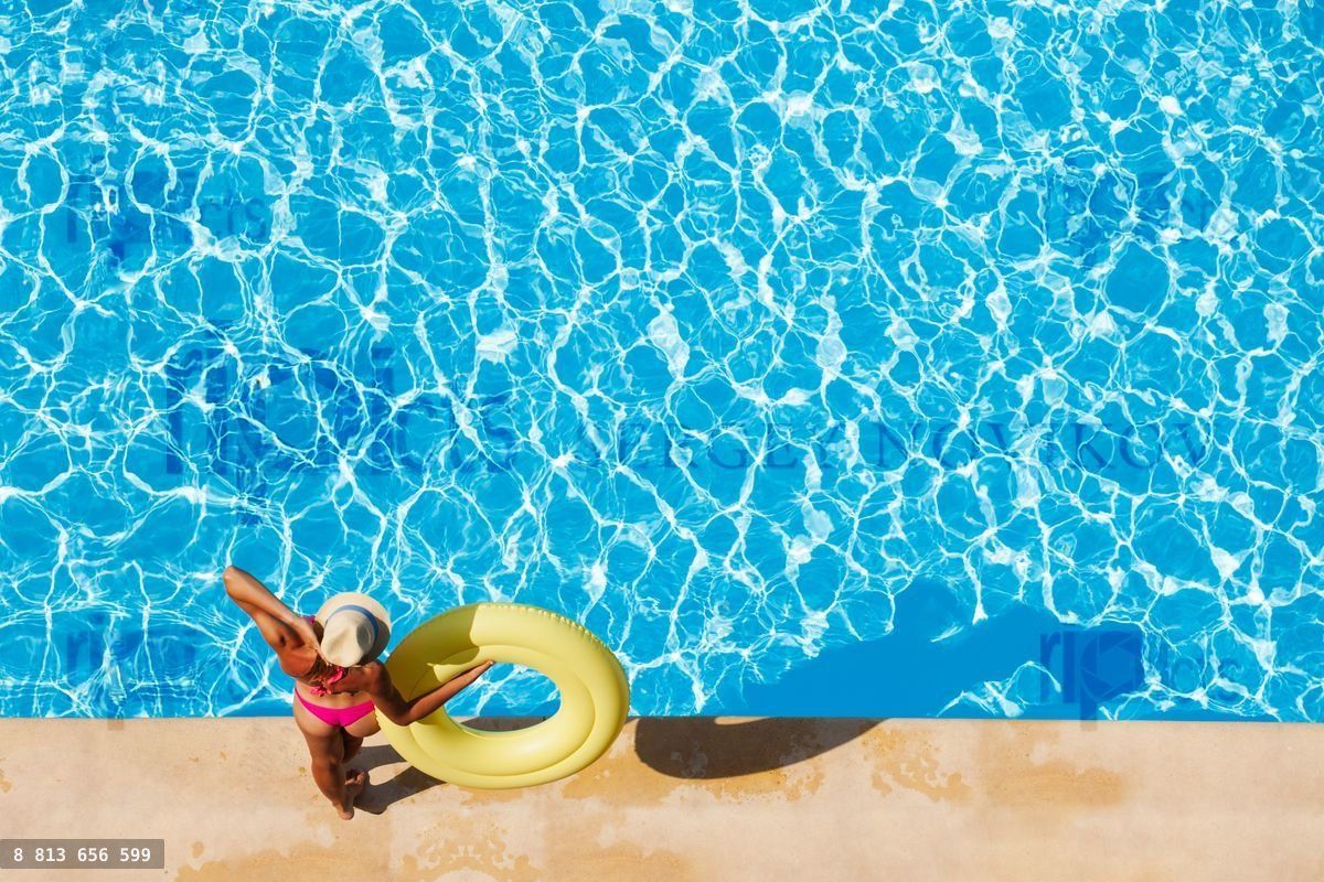 Woman in straw hat at poolside with rubber ring