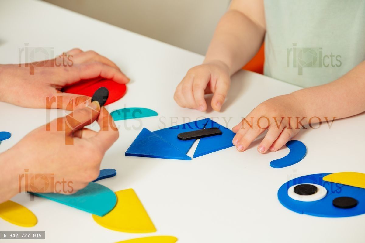 Girl child's hand put together shapes to create a house