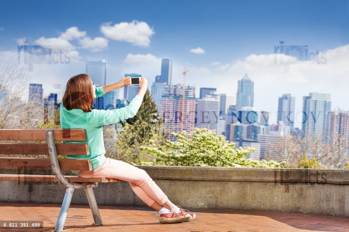Woman take photo with cellphone of Seattle