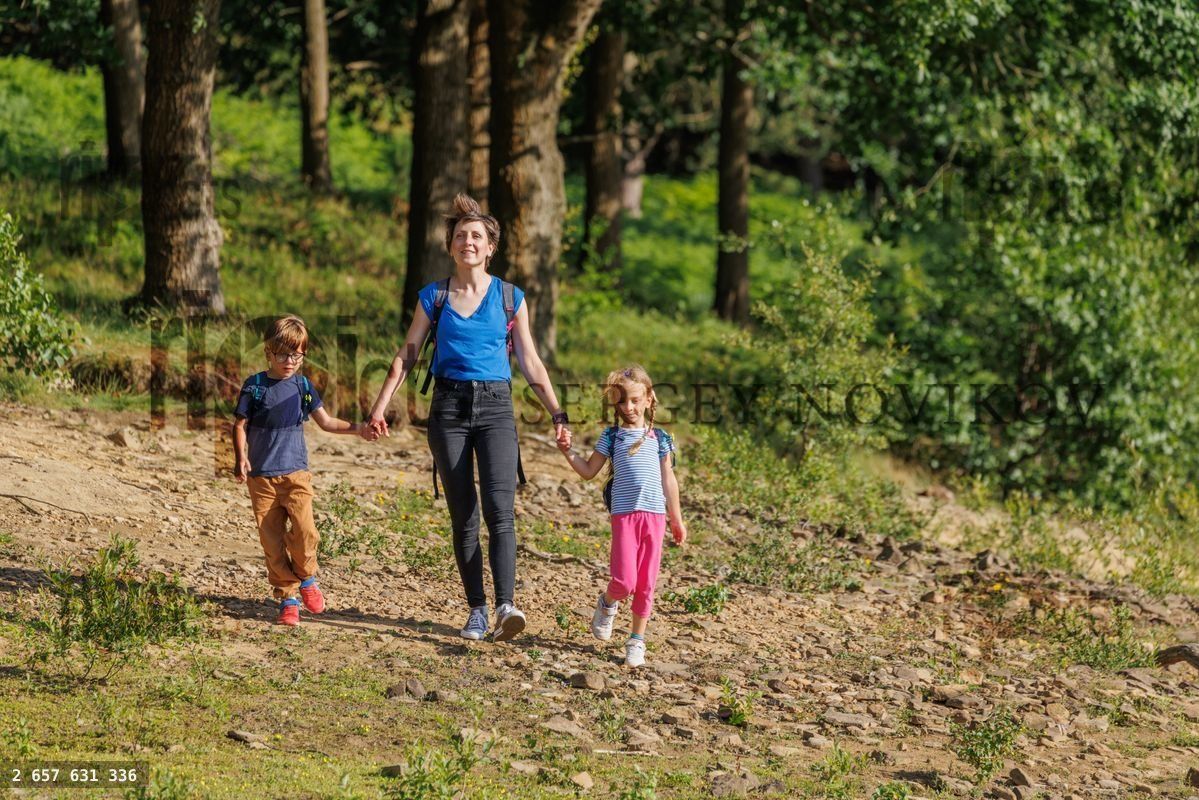 Mother and two children hiking together in a green forest scene