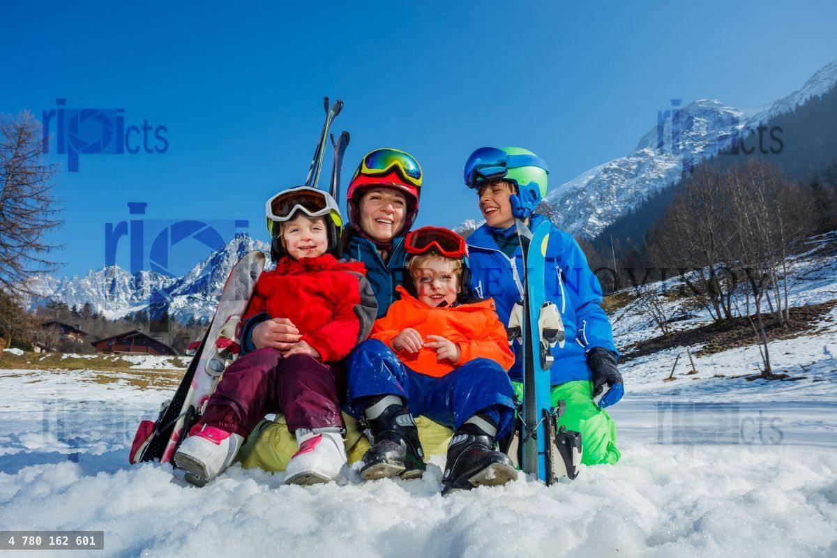 Family of mom and small kids sit with ski in snow over mountain