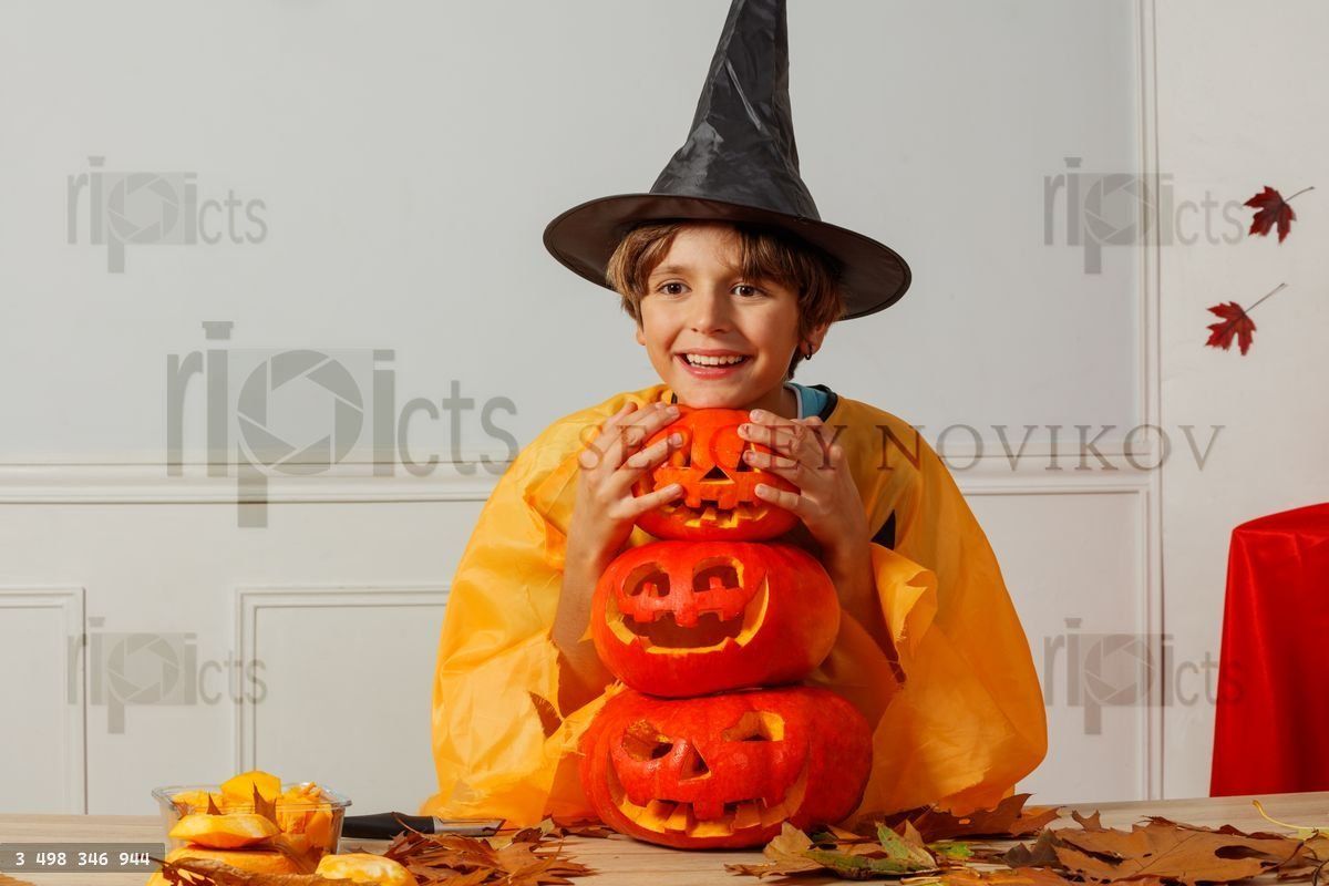 Young boy in wizard hat enjoy Halloween hugging spooky pumpkins