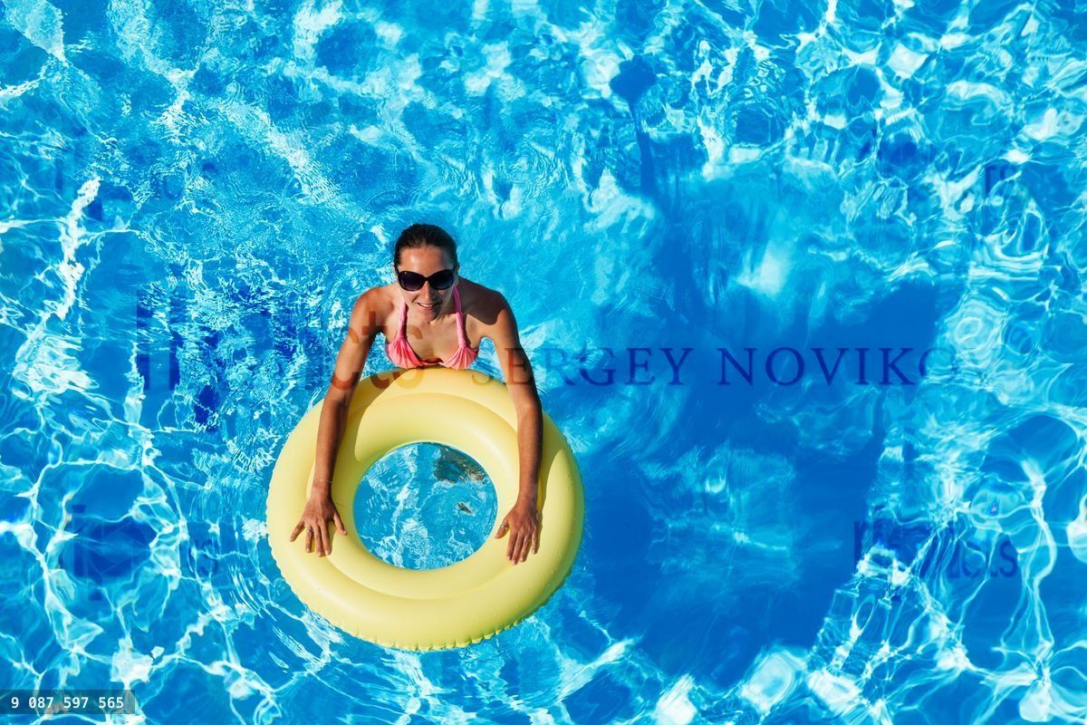 Young woman swimming in the pool with rubber ring