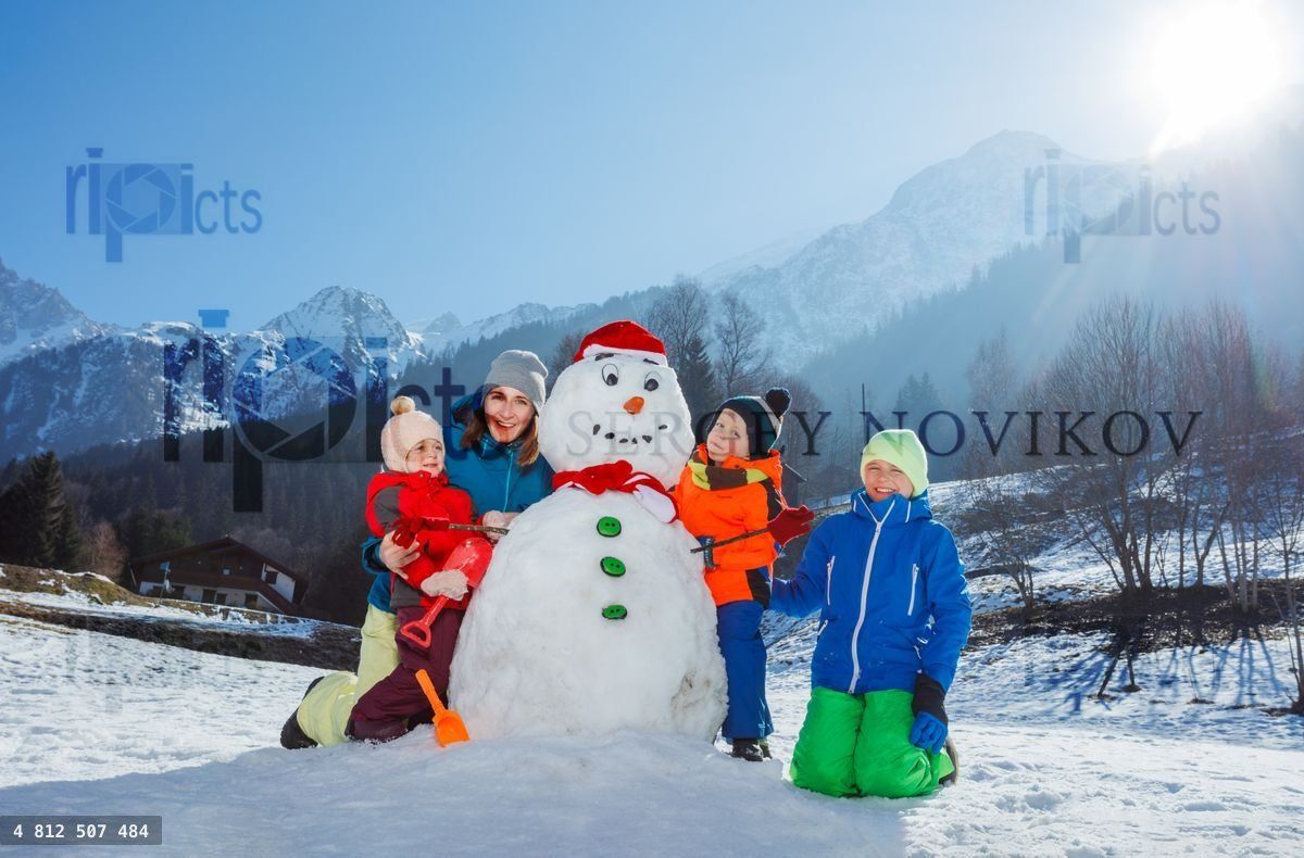 Famille avec mère et trois enfants construisant un bonhomme de neige