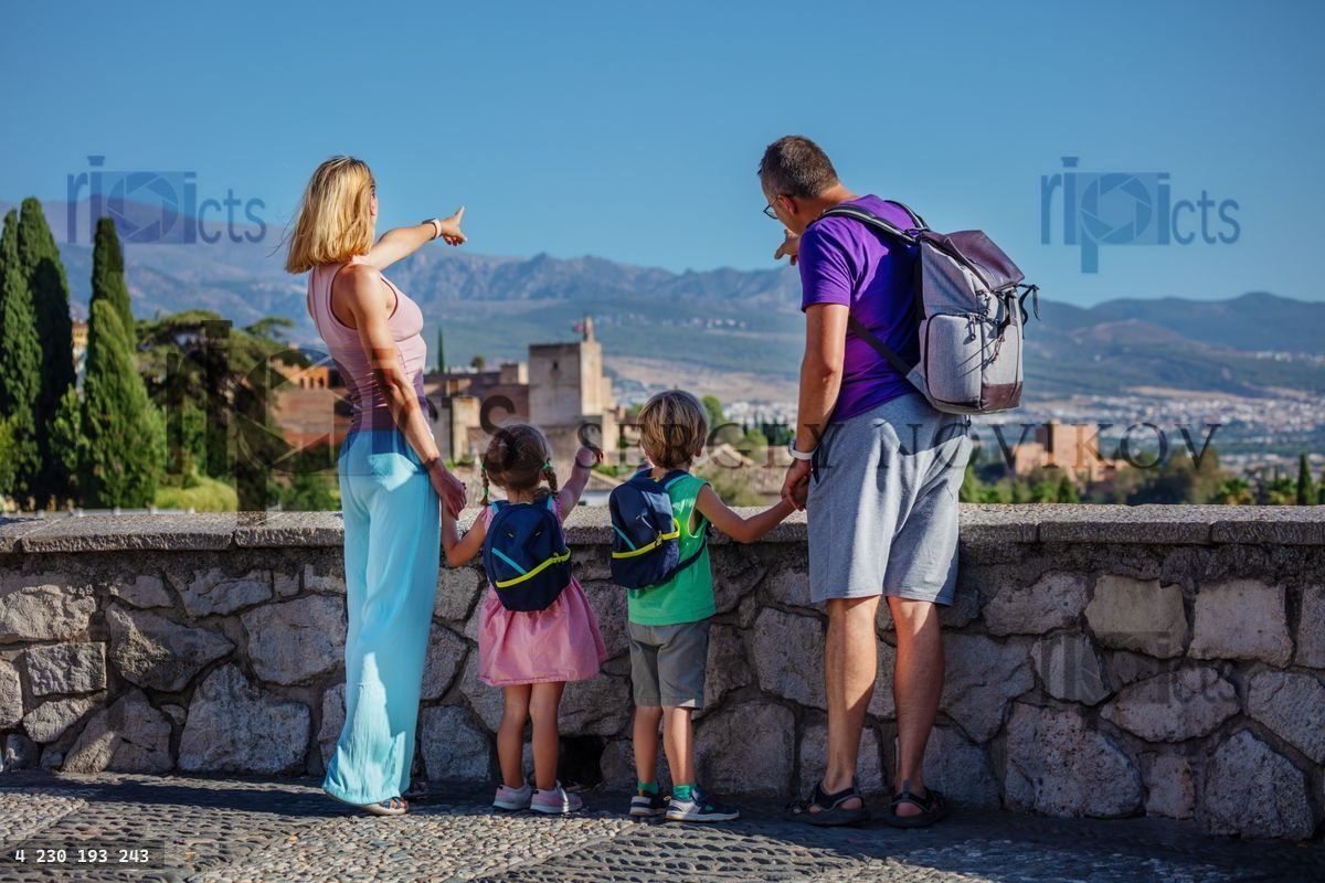 Young parents show kids famous Alhambra palace from viewpoint