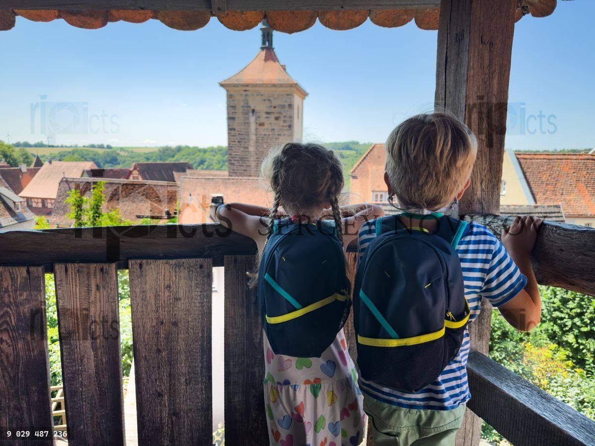 Young explorers admire Rothenburg townscape from wooden balcony