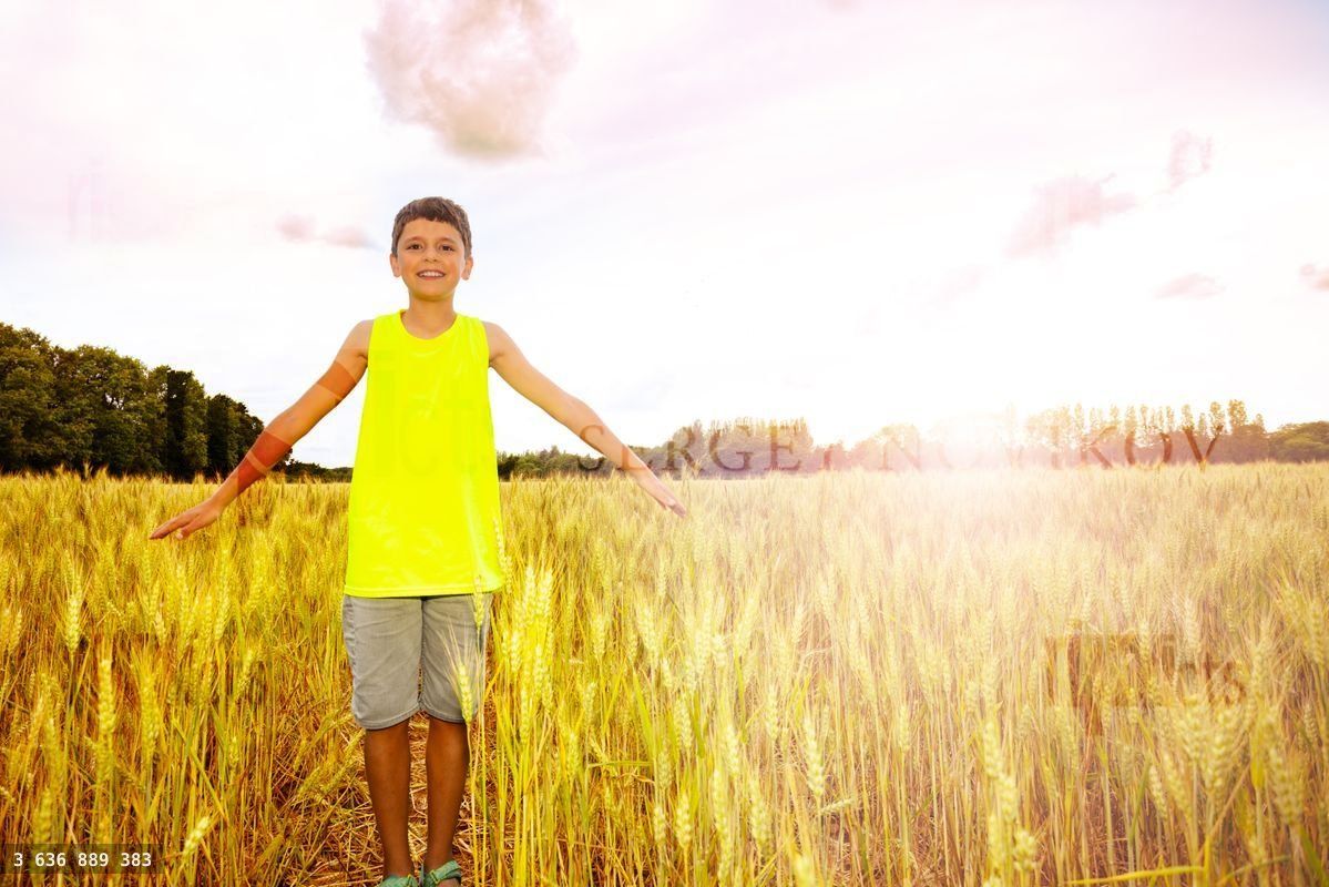 Young boy stand in the wheat field lifting up hands