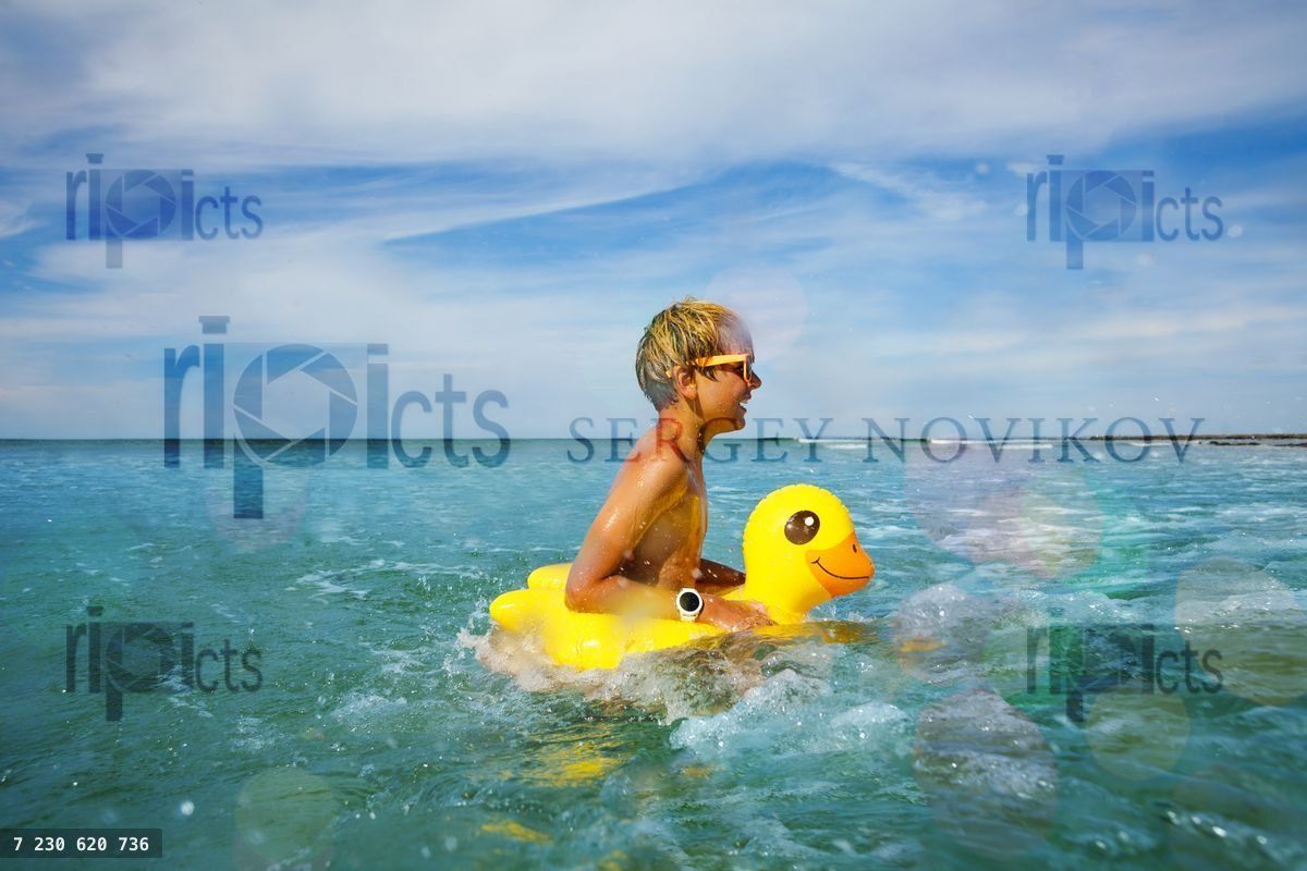 Fun at ocean boy in sunglasses swim with inflatable duck
