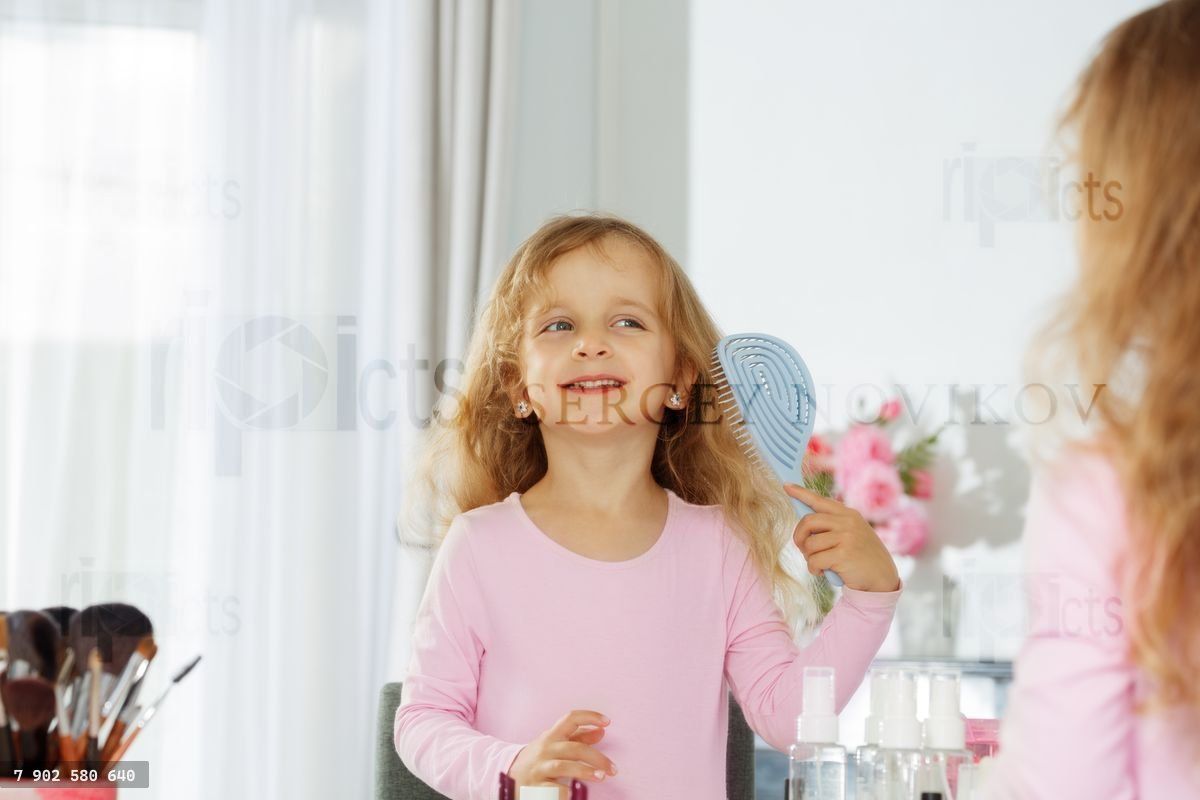 Young girl smiling, brushing hair, enjoying her beauty routine
