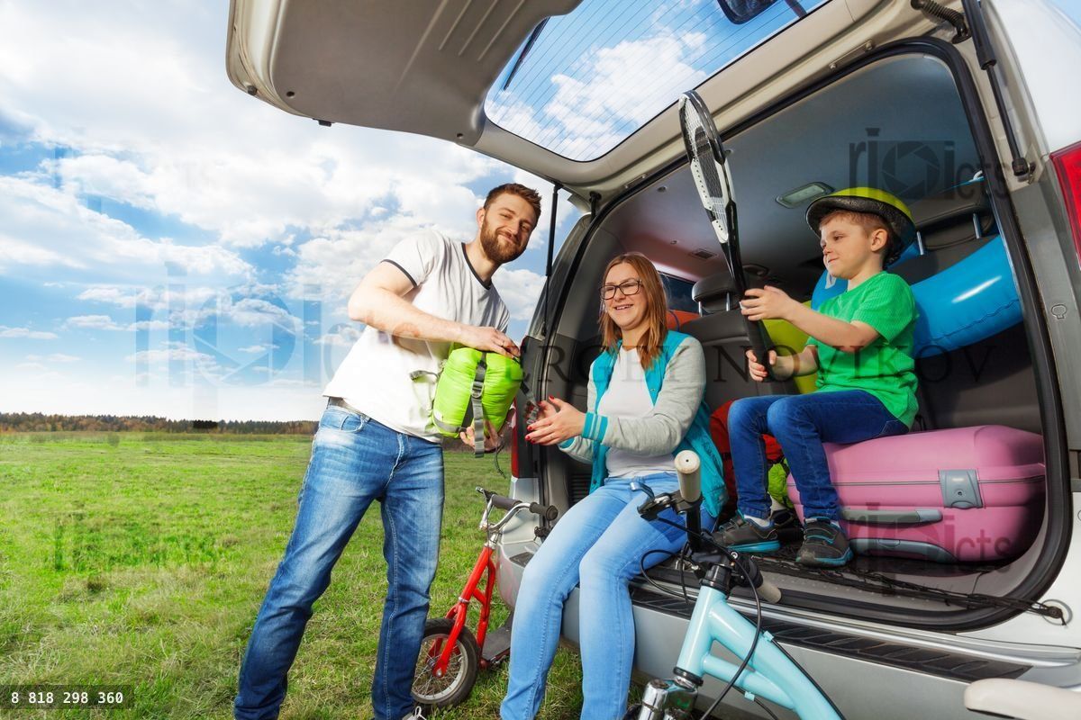 Young family loading luggage boot for the car trip