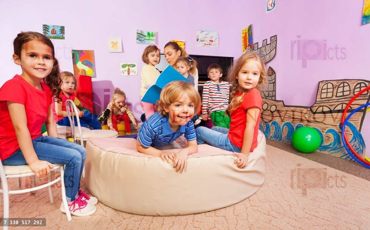Group of kids listen to the teacher reading a book