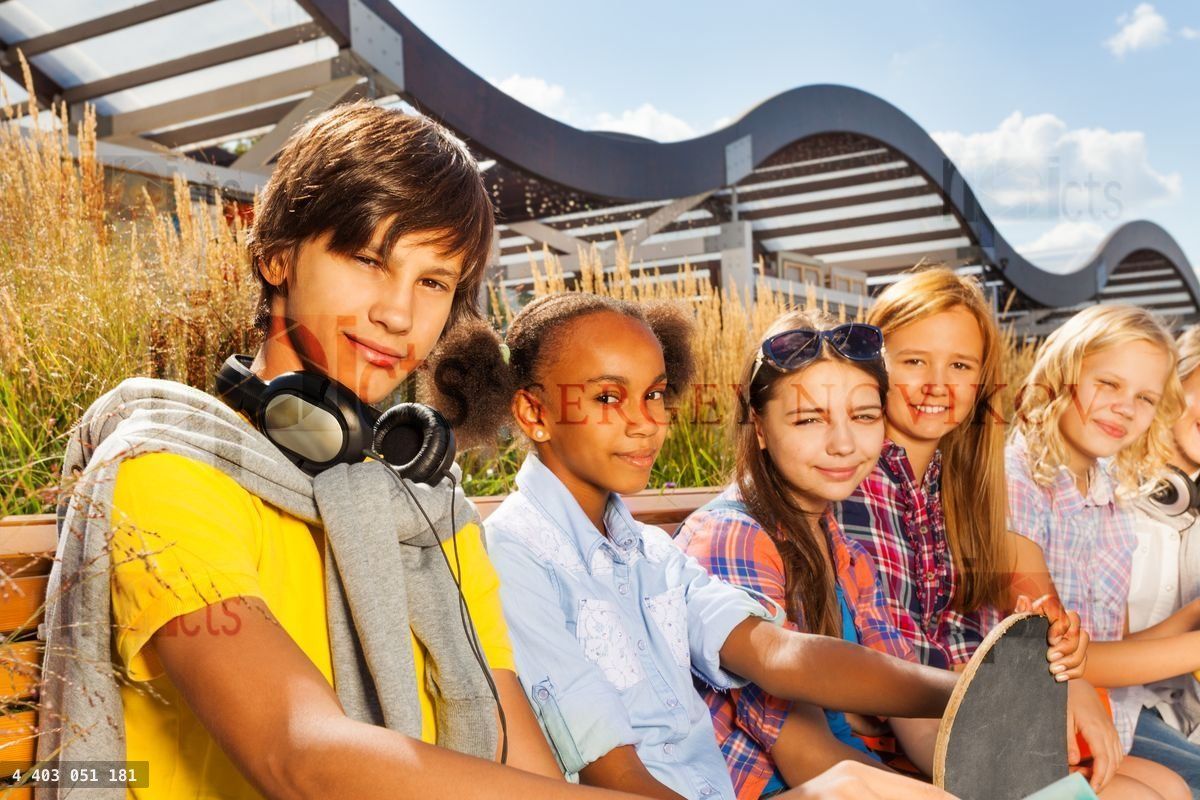 Boy with smiling girls on bench holding skateboard