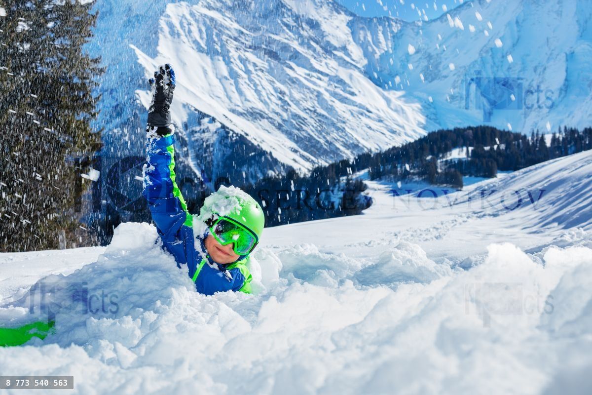 Fun with snow happy boy play laying in snowdrift